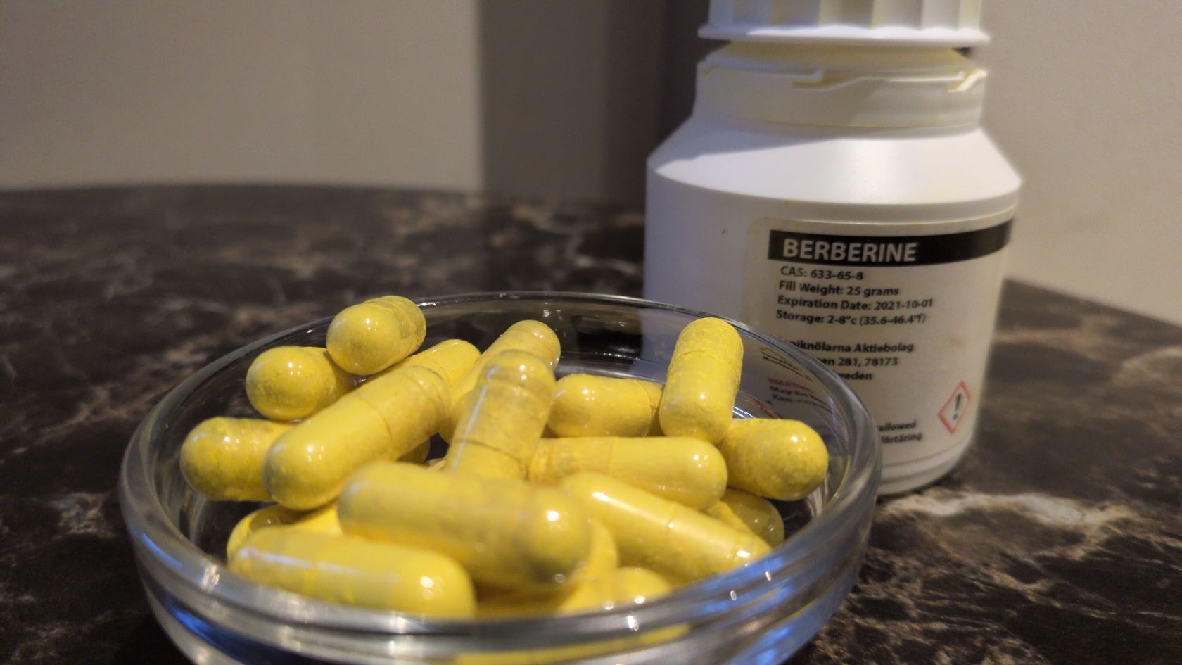 Berberīna HCl kapsulas stikla bļodā blakus pudelei ar BERBERINE etiķeti